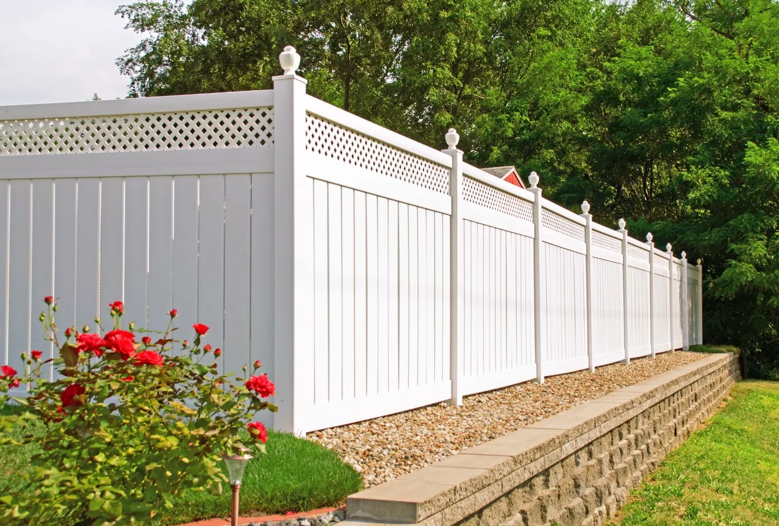 White vinyl privacy fence with decorative lattice in a landscaped yard