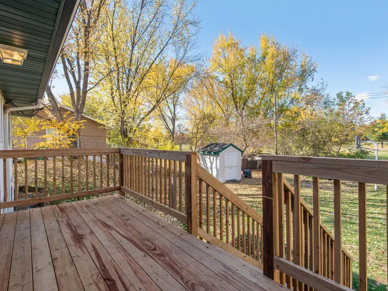 Wood deck with railings and stairs overlooking a backyard